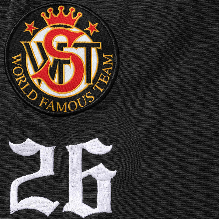 Close-up of the World Famous Team crown crest patch and embroidered 26 on black ripstop