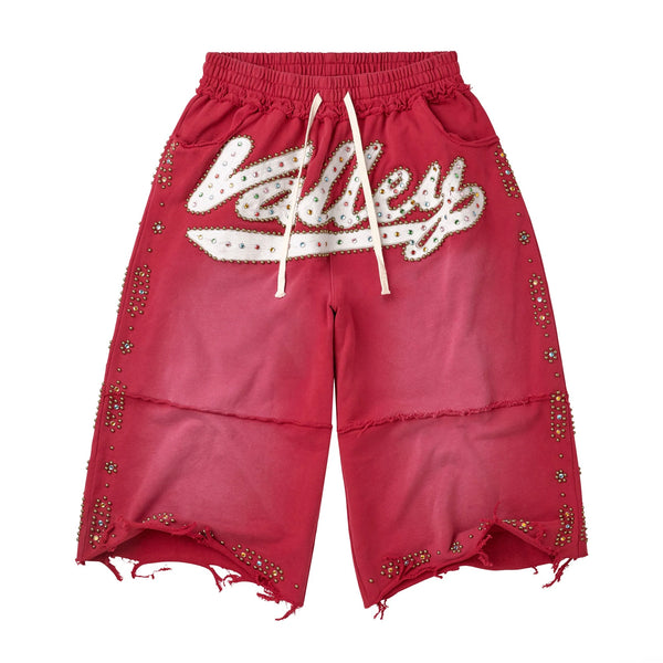 Vale Red Skittle 3/4 Shorts, faded red baggy long shorts with a studded white valley script, gold side studs and frayed hems