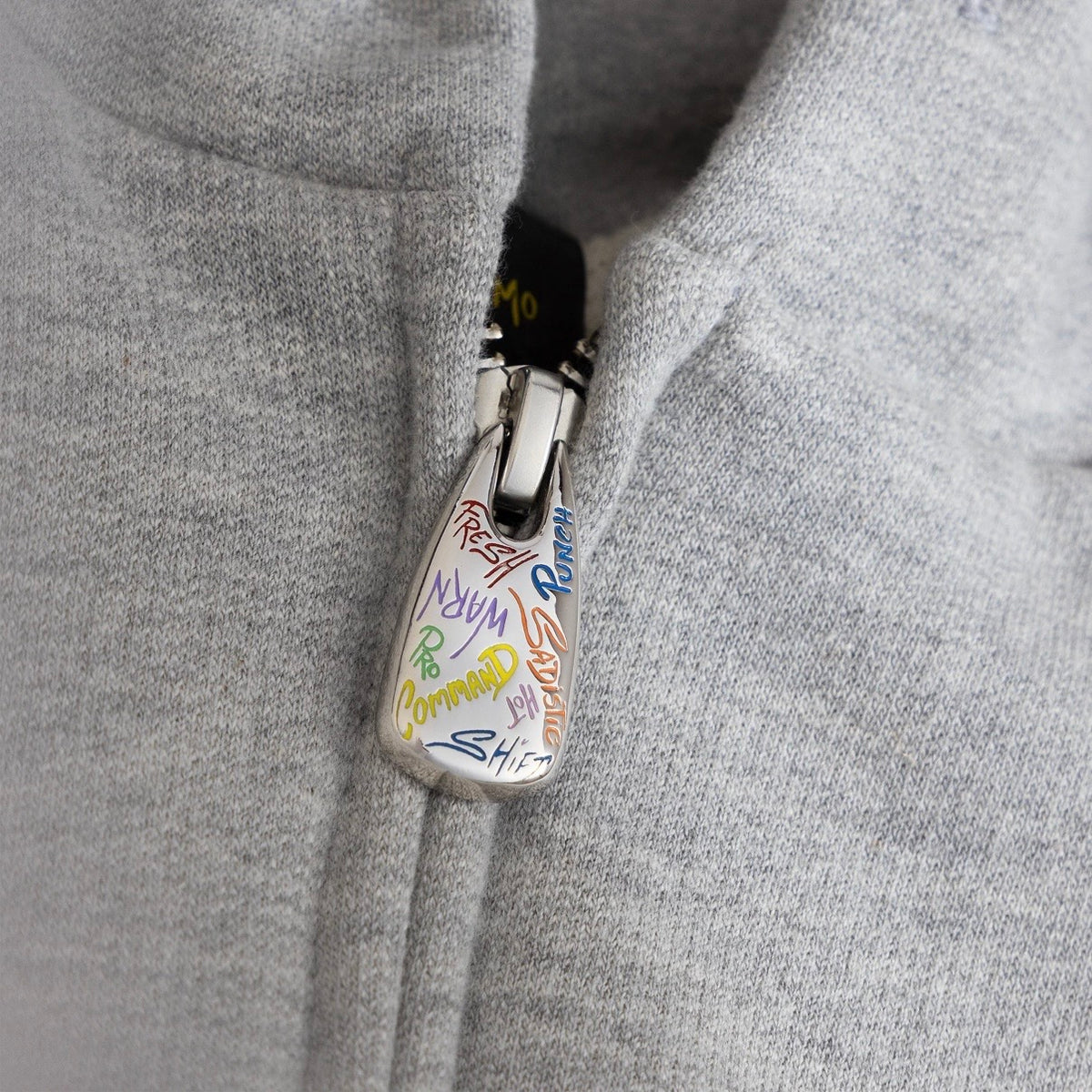 Matty Boy Sadistic Zip Hoodie zip detail — custom white graffiti zip puller against the grey knit