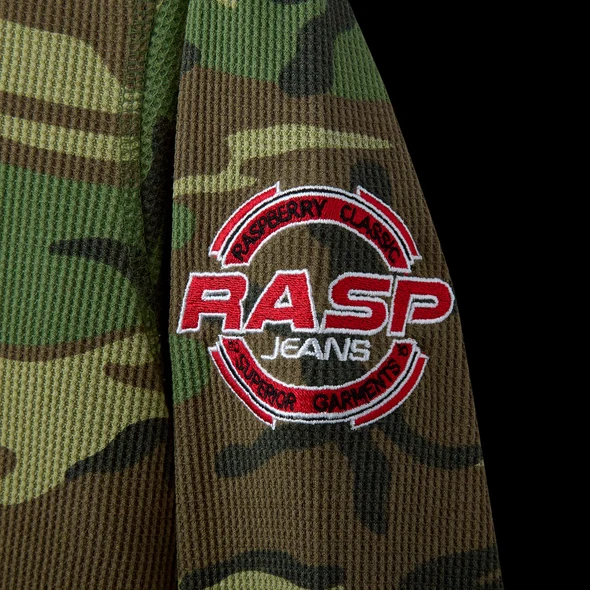 Close-up of the red circular RASP JEANS roundel patch on the camo sleeve