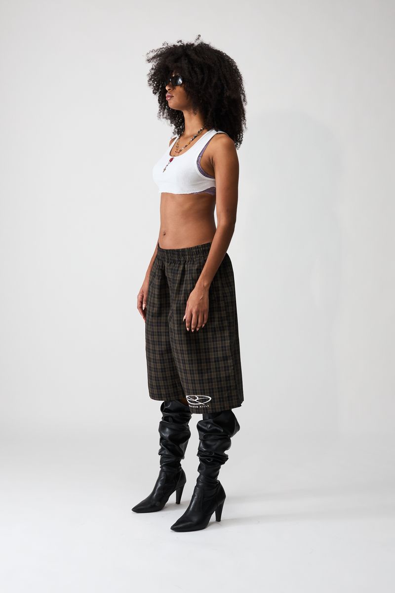 Boredom Kills Black Brown Plaid Track Shorts on a model at a three-quarter angle with heeled black boots