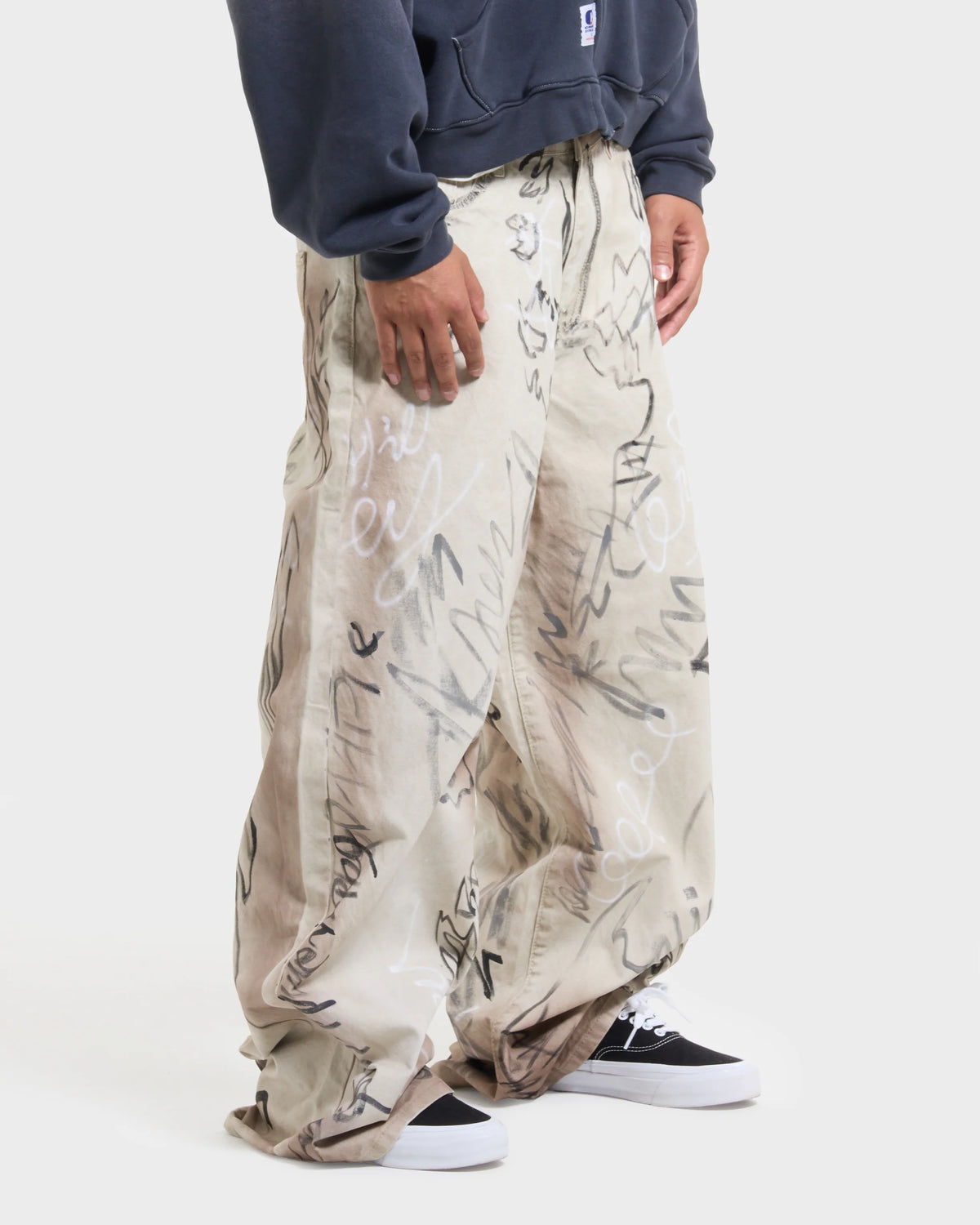 Full-length front lookbook shot of the model in the ecru graffiti trousers
