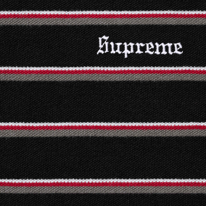 Close-up of the white Supreme script embroidery on the black striped polo knit