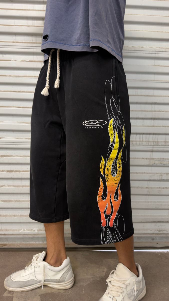 Boredom Kills Up In Flames 3/4 Shorts front on a model — flames on both legs, cream drawcord, below-knee length