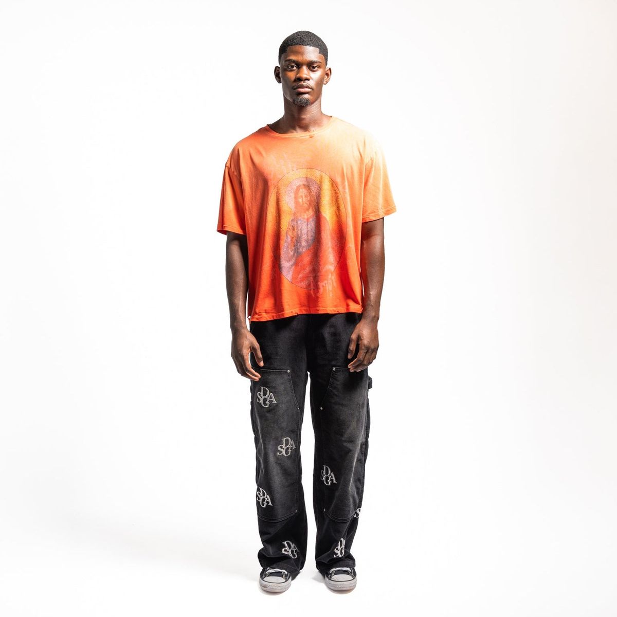 Model wearing the Stile De Amor El Rey orange tee with black printed pants