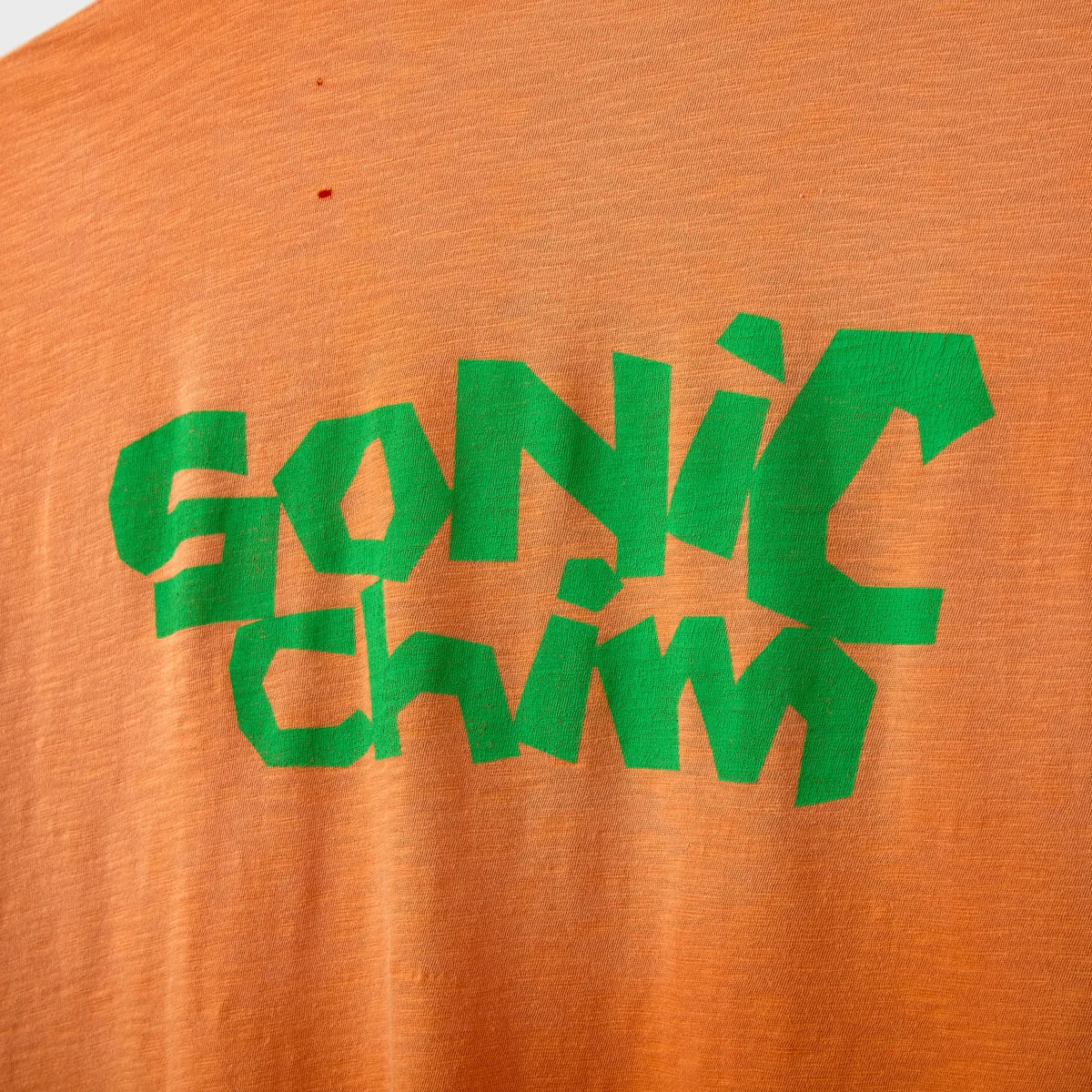 Close-up of the green SONIC CHIM back print on orange slub cotton
