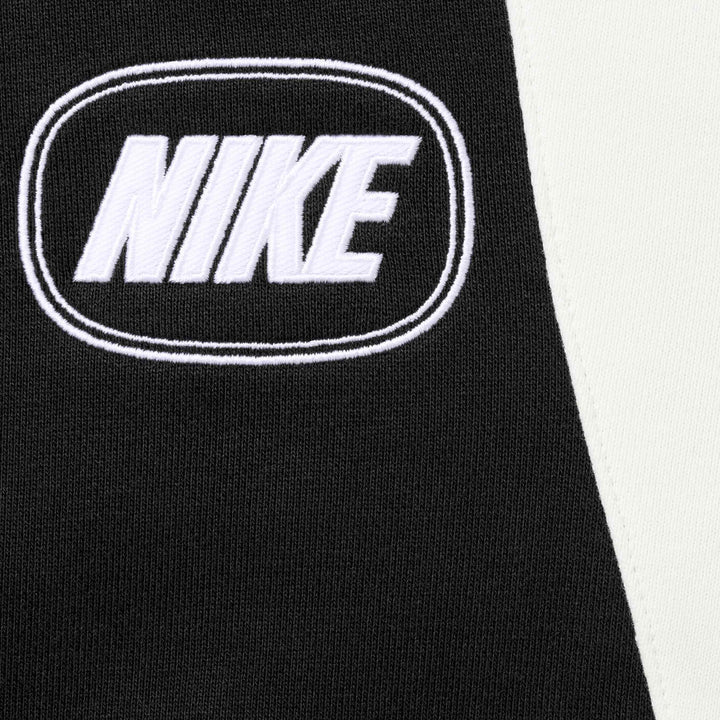 Close-up of the oval NIKE logo and white side panel on the black sweatpants