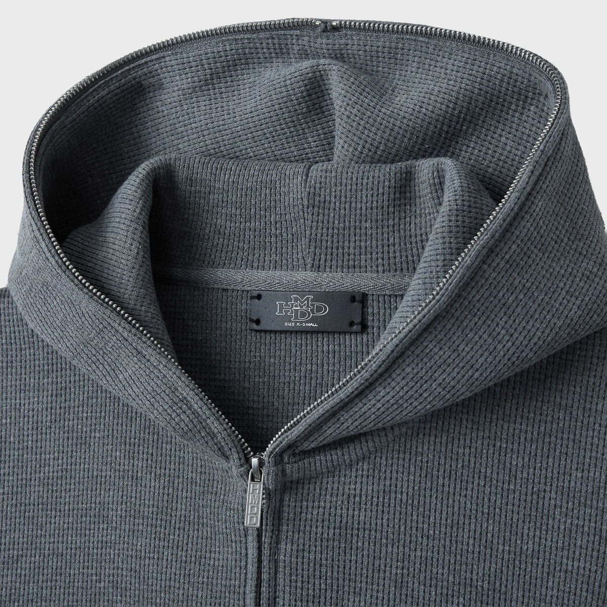 Close-up of the grey hoodie collar and hood with dark woven HMDD neck label