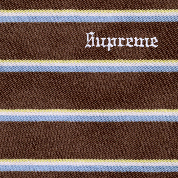 Close-up of the white Supreme script embroidery on the brown striped polo knit