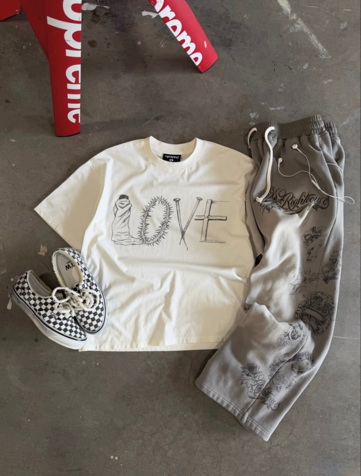 Flat-lay of the grey sweatpants styled with a cream LOVE tee and checkerboard slip-ons