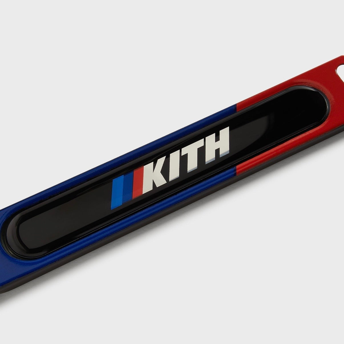 Kith BMW Multi License Plate Holder, close-up of the lower bar, Kith wordmark and M stripes over a blue to red gradient