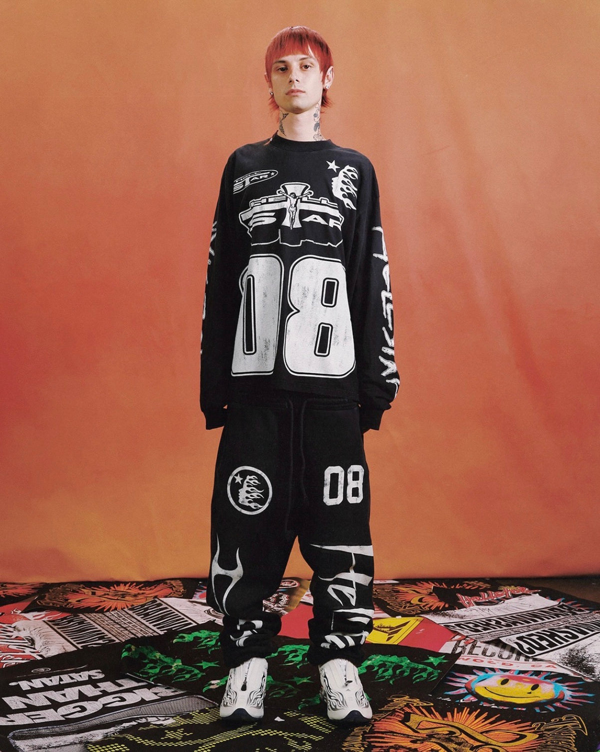 Hellstar Black Racer Sweatpants worn with the 08 long sleeve on an orange backdrop