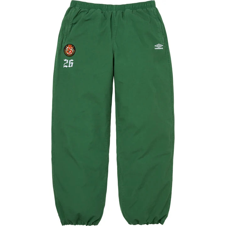 Supreme x Umbro cotton ripstop track pants in green with a crest patch and 26 on the left thigh and Umbro logo on the right, front view