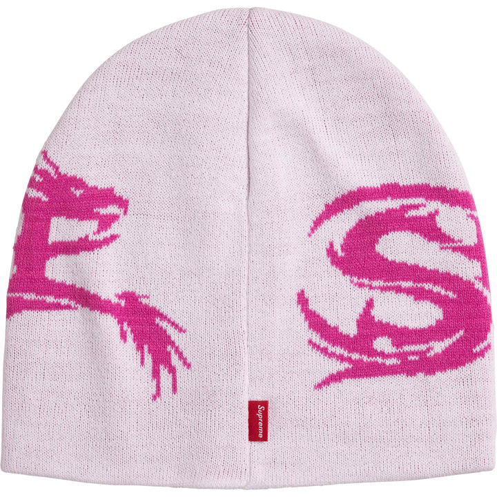 Back of the pale Supreme Dragon beanie showing the magenta dragon tail, a large S and a red woven tab