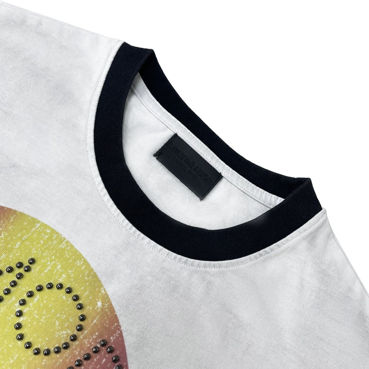 Stile De Amor White Buon Vino T-Shirt, close-up of the black ribbed ringer collar, the black woven neck label and black rhinestones set into the AMOR lettering