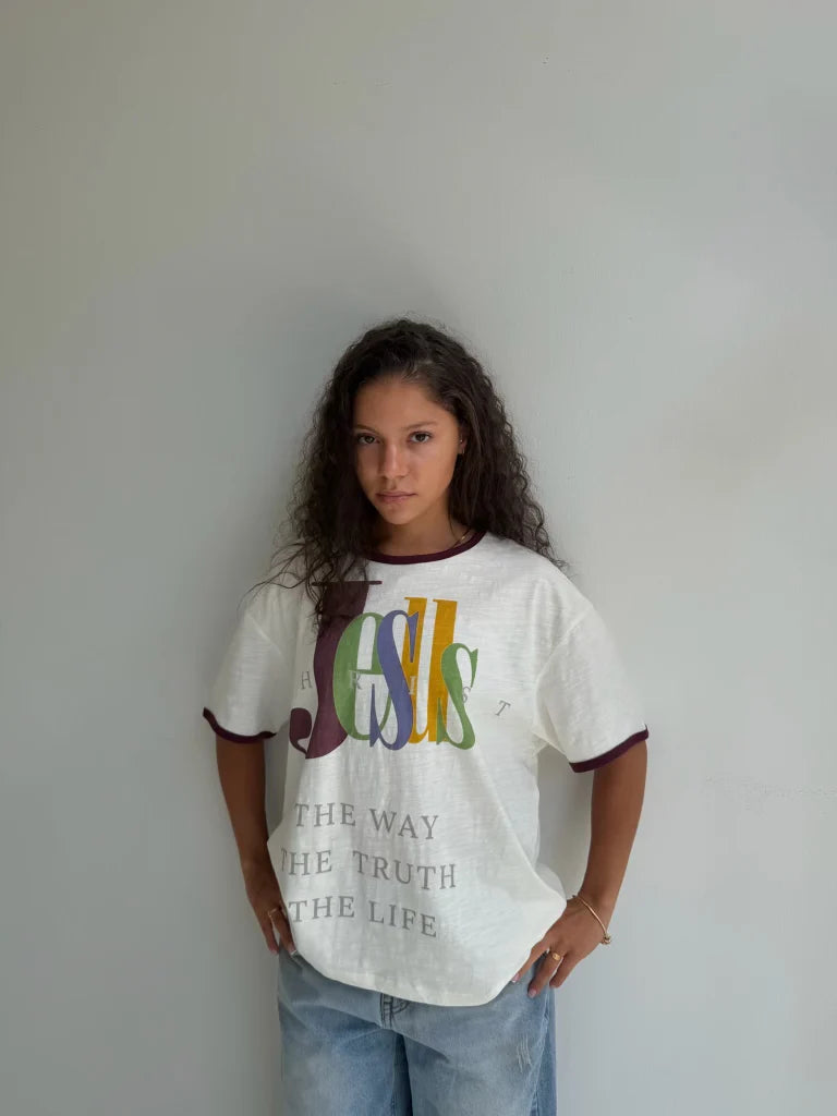 We Are Righteous The Truth Ringer Tee worn with blue jeans against a grey studio wall