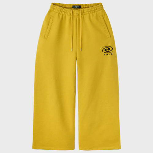 HMDD Hurricane Sweatpants, mustard yellow wide-leg sweatpants with white drawstring, welt pockets and black swirl logo above CHIM