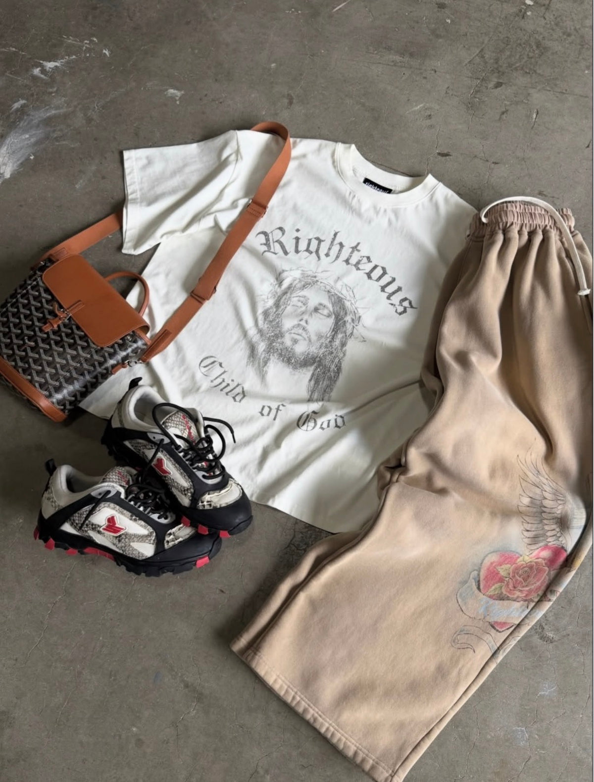Flat-lay of the tan sweatpants styled with a cream Righteous tee, bag and sneakers