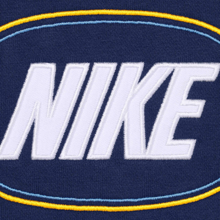 Close-up of the white NIKE applique inside light blue and gold ovals on navy fleece