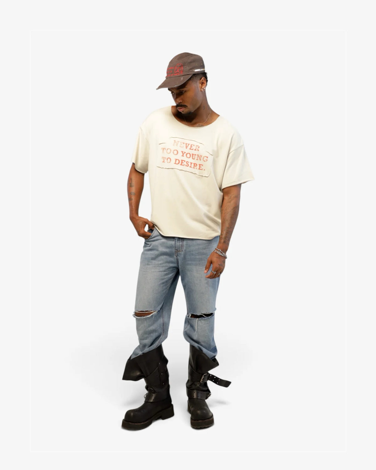 Male model wearing the cream NEVER TOO YOUNG tee with ripped light blue jeans