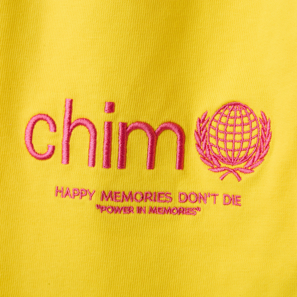 HMDD Yellow Program 3/4 Shorts, close-up of the pink chim globe embroidery reading Happy Memories Don't Die on yellow fabric