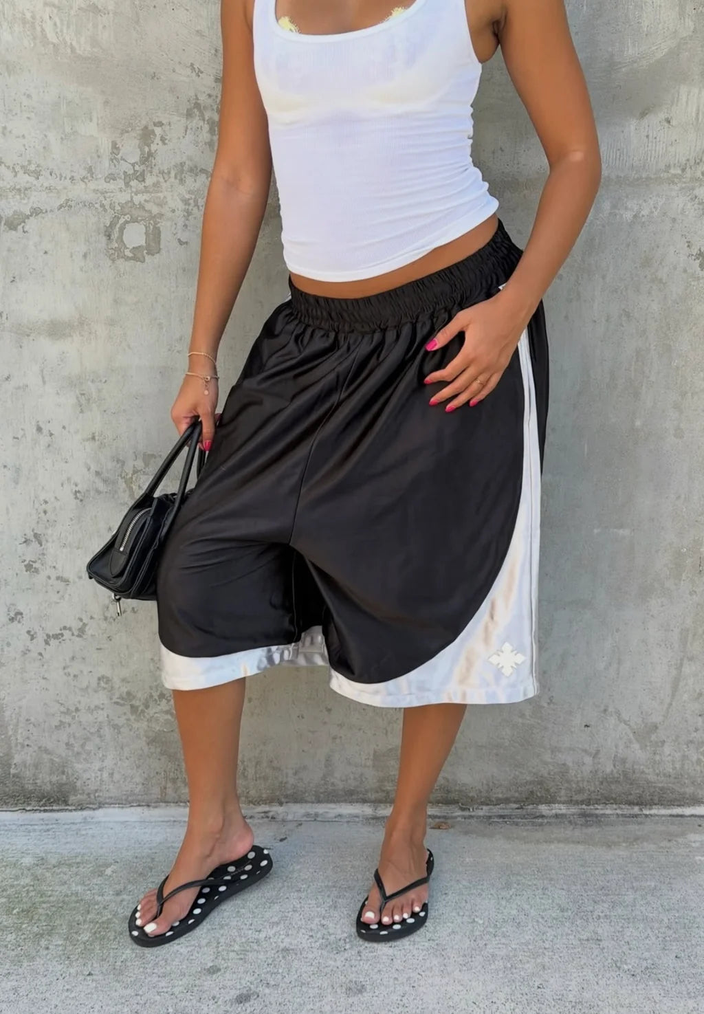 We Are Righteous Sandler Gym Shorts worn with a white ribbed tank against a concrete wall