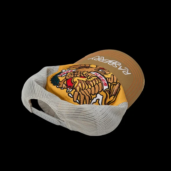 Rear three-quarter of the cream mesh trucker cap with tan brim and eagle front