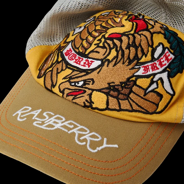 Close-up of the embroidered eagle with BORN and FREE banners above the tan brim