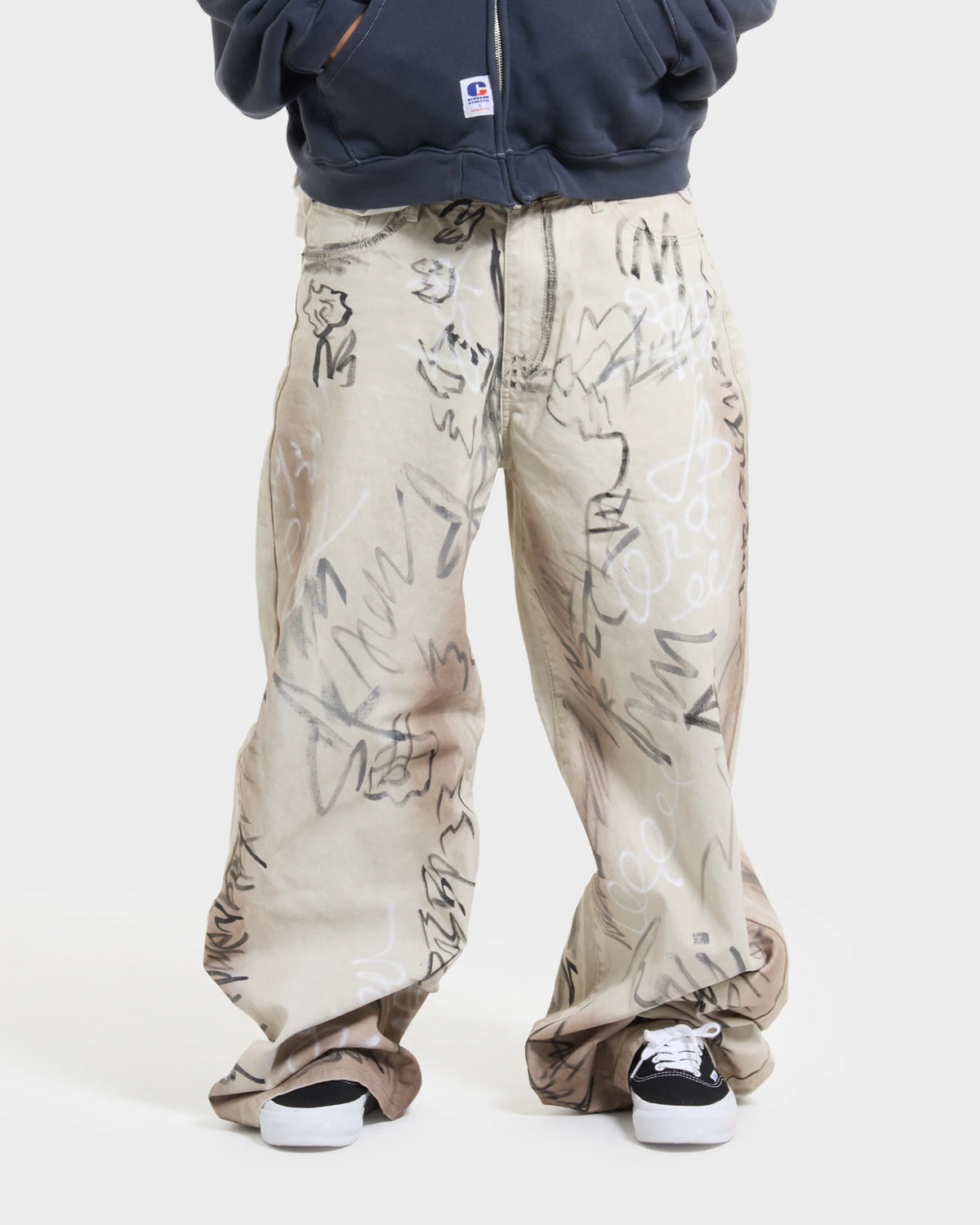 Model in a grey Chim hoodie and the baggy ecru graffiti trousers, full length