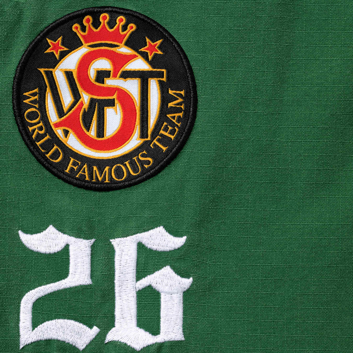 Close-up of the World Famous Team crown crest patch and embroidered 26 on green ripstop