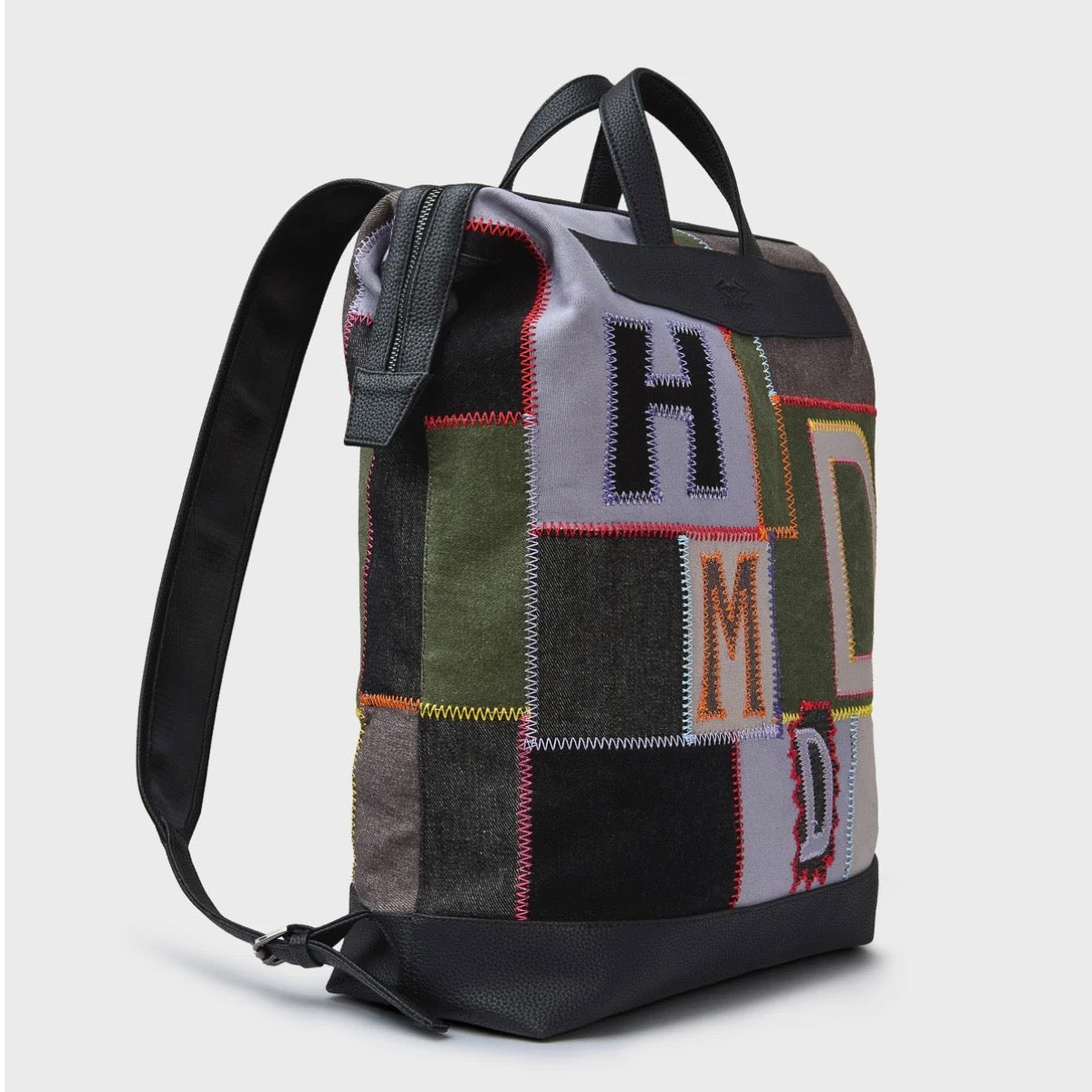 HMDD Hopscotch Box Bag, angled view of a patchwork backpack in green and grey with appliqued H, M and D letters and black straps