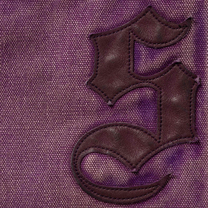 Close-up of the stitched leather blackletter applique on the Purple Double Knee Painter Pants