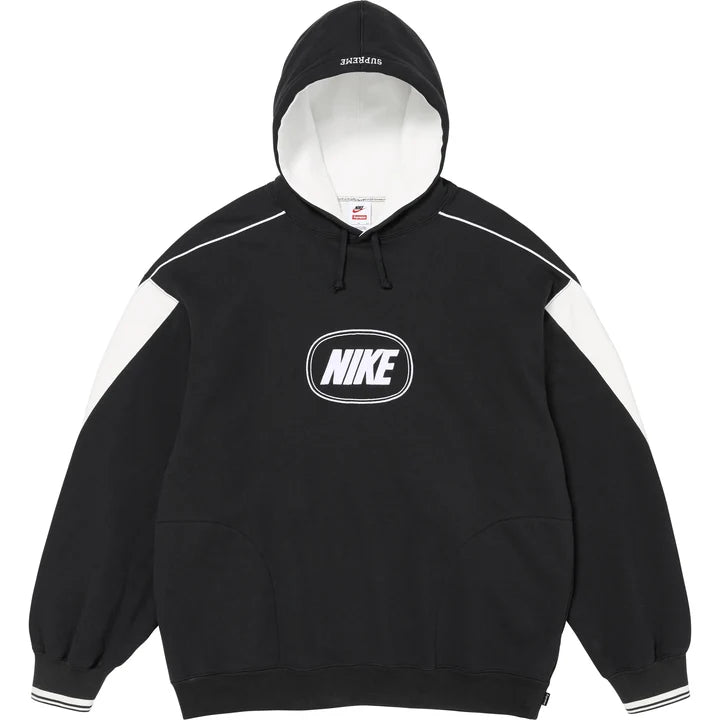 Supreme x Nike hoodie in black with curved white shoulder panels, white piping, white hood lining and an oval NIKE logo on the chest, front view