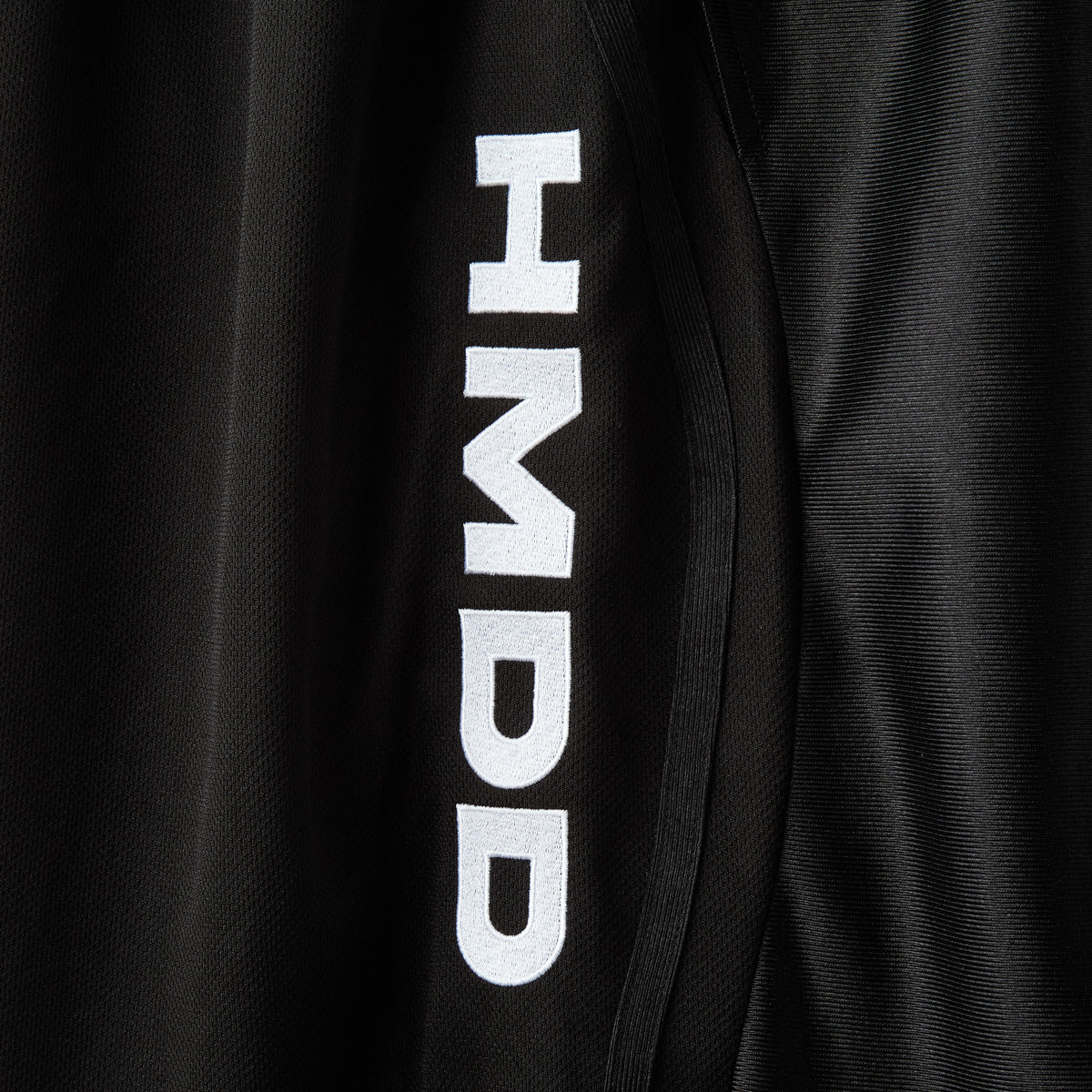 HMDD Black Mixtape Shorts, close-up of the vertical white HMDD print on the black mesh leg panel