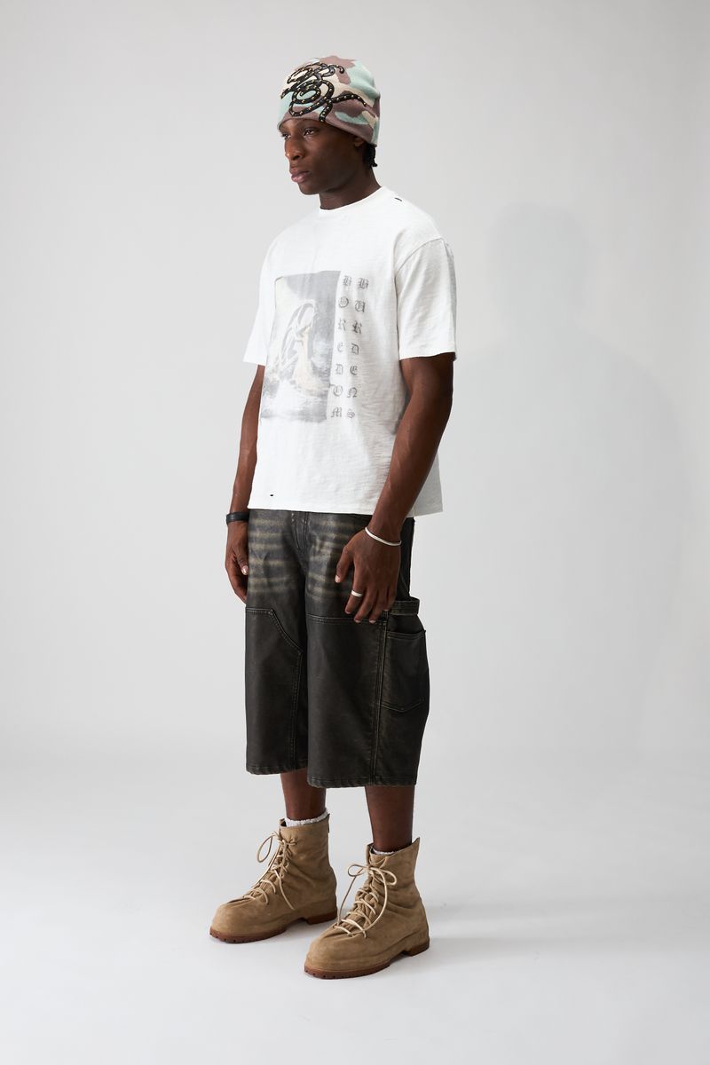 Boredom Kills Black Leather Shorts, three-quarter view of the model in the faded baggy shorts and tan boots
