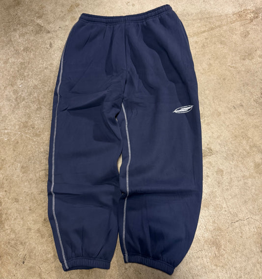 No Feelings navy sweatpants laid flat, with contrast stitched seam lines down the legs, a small logo on the thigh and elastic cuffs