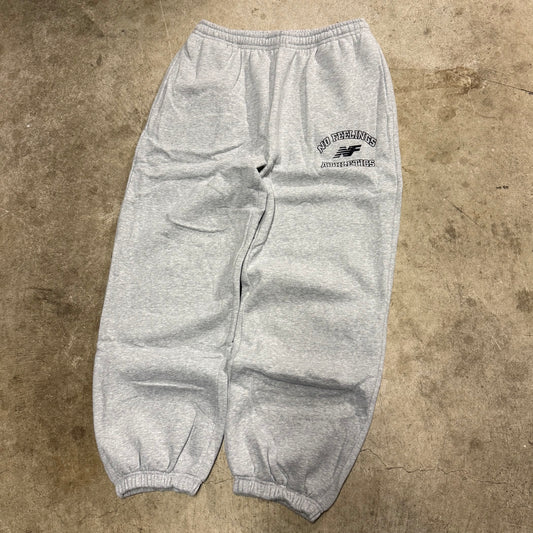 No Feelings heather grey sweatpants laid flat, with a navy athletics graphic on the upper thigh and elastic cuffs