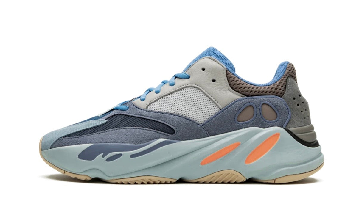Adidas Yeezy 700 Carbon Blue, grey and navy panelled runner in profile, orange sole pods on a pale blue wavy midsole