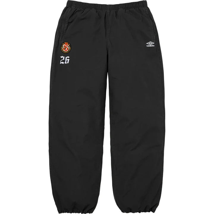 Supreme x Umbro cotton ripstop track pants in black with a crest patch and 26 on the left thigh and Umbro logo on the right, front view