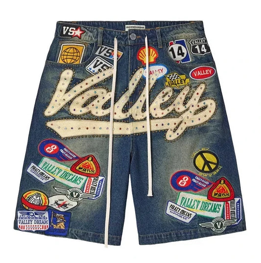 Front of the Vale Blue 1980s Jorts in washed mid-blue denim, covered with Valley Dreams patches and a white chainstitched Valley script down the leg