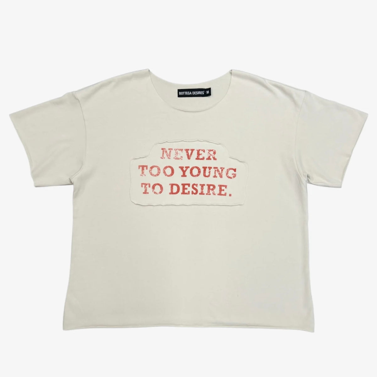 Cream boxy tee with rust-red NEVER TOO YOUNG TO DESIRE applique chest print