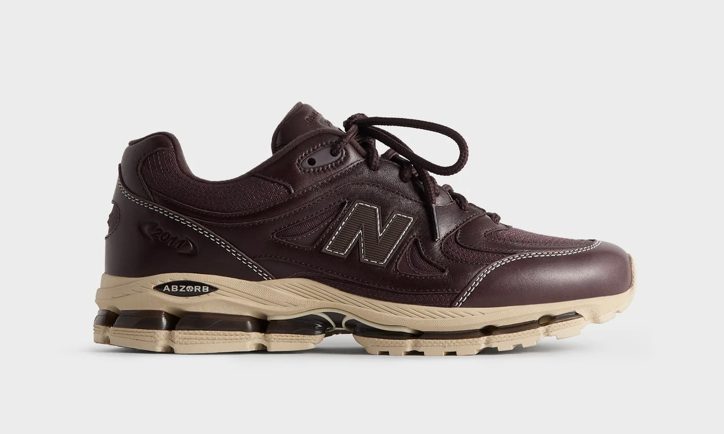 Kith New Balance 2011 Bark, angled side view of the dark brown leather shoe on a grey background