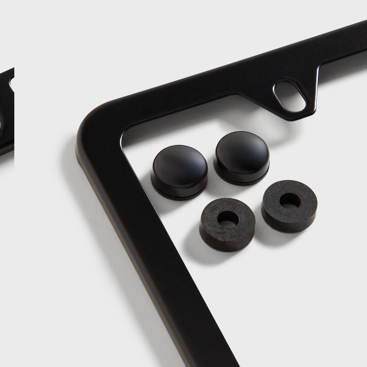 Kith BMW Black License Plate Holder, angled view of one corner of the black frame with four black screw caps