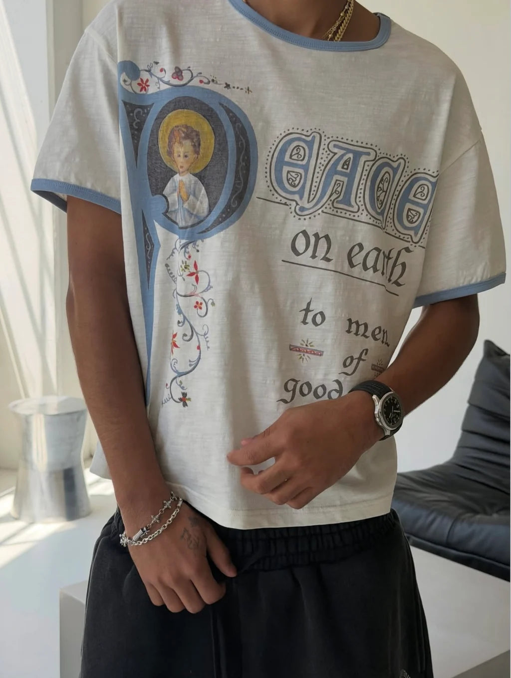 We Are Righteous Peace On Earth Ringer Tee worn with black trousers and beaded bracelets