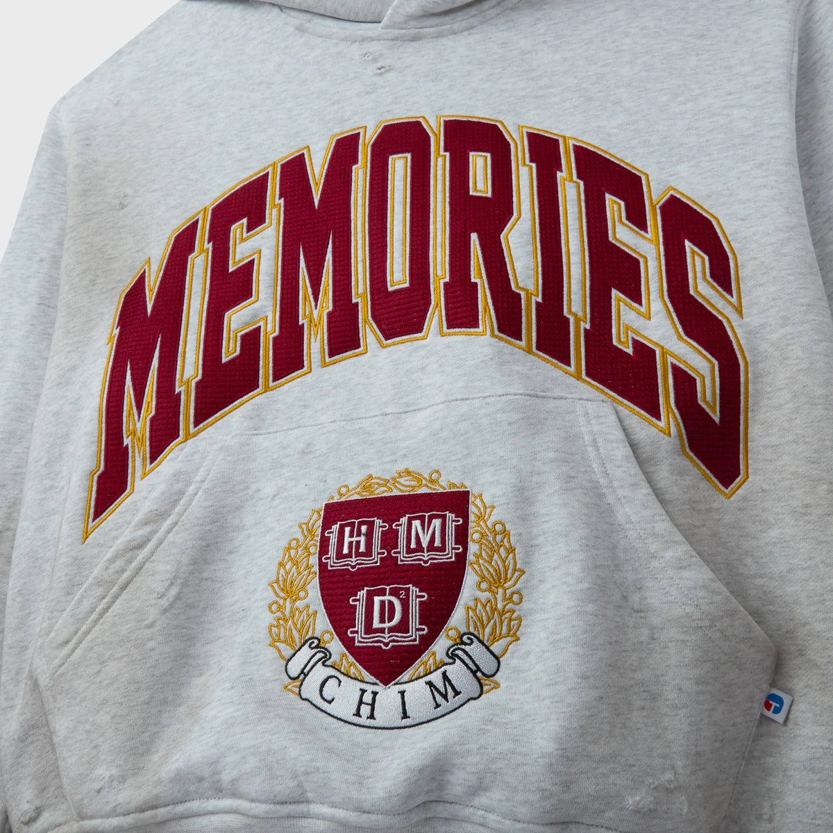 HMDD Griffin Hoodie close-up of the Memories lettering and the laurel crest above the hem