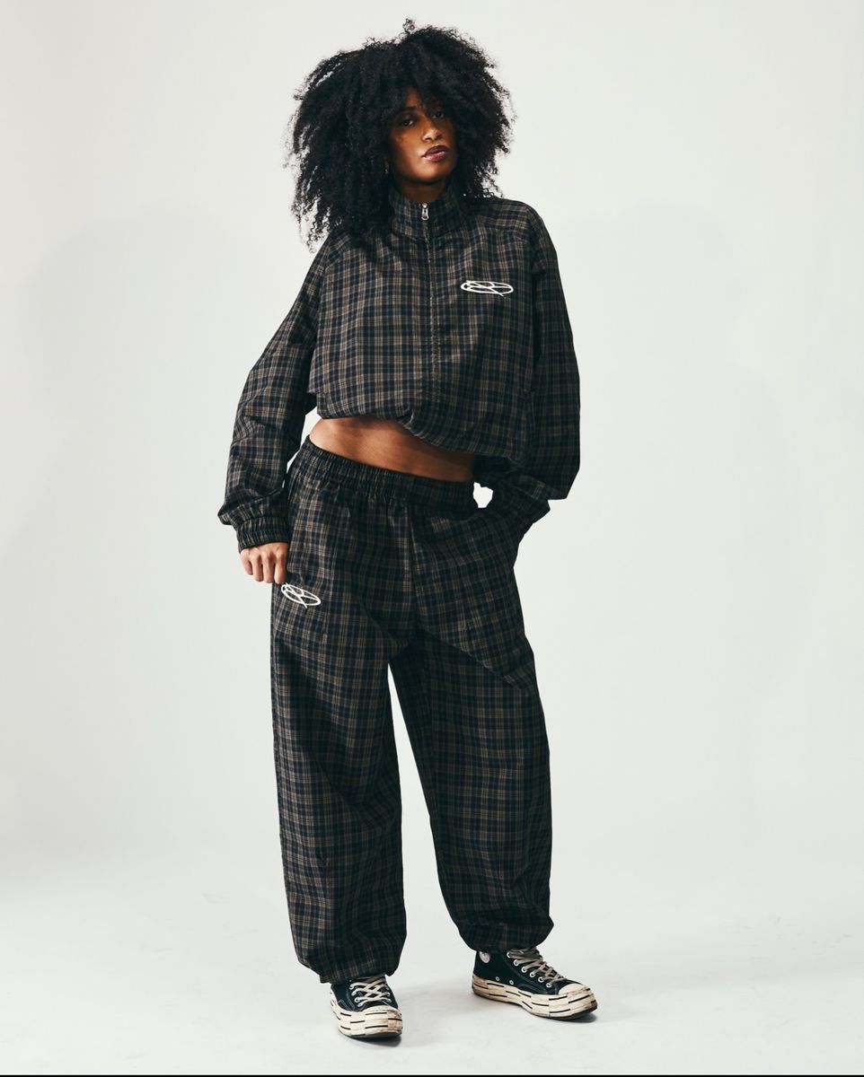 Boredom Kills Black Brown Plaid Track Jacket worn boxy and short by a studio model over the matching plaid pants