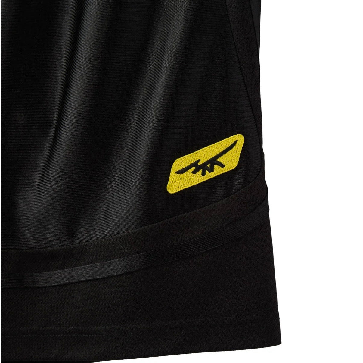 HMDD Black Mixtape Shorts, close-up of the yellow winged HMDD logo printed on the black mesh above the hem binding
