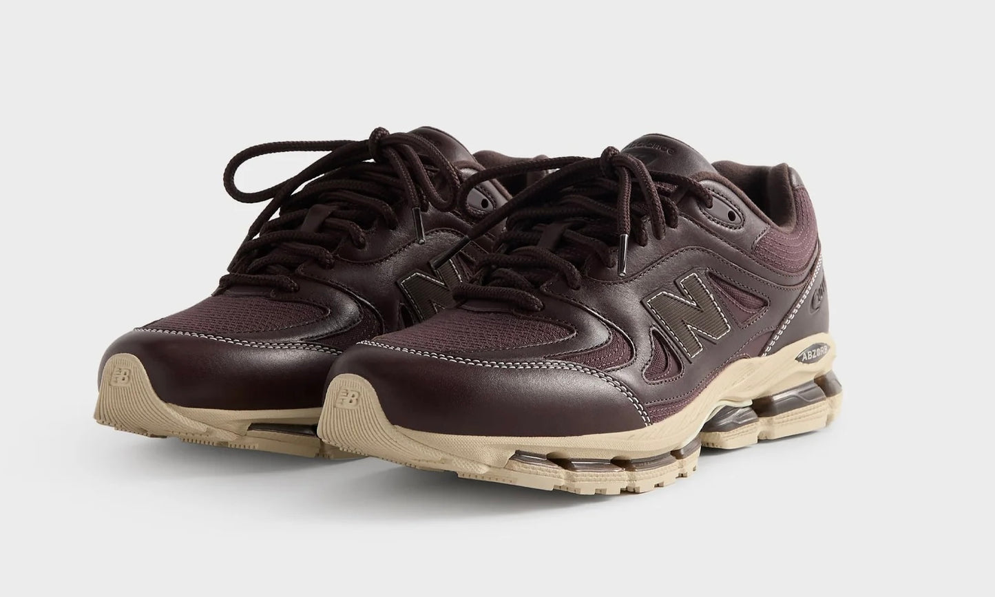 Kith New Balance 2011 Bark, angled front view of the pair, dark brown leather uppers on cream midsoles