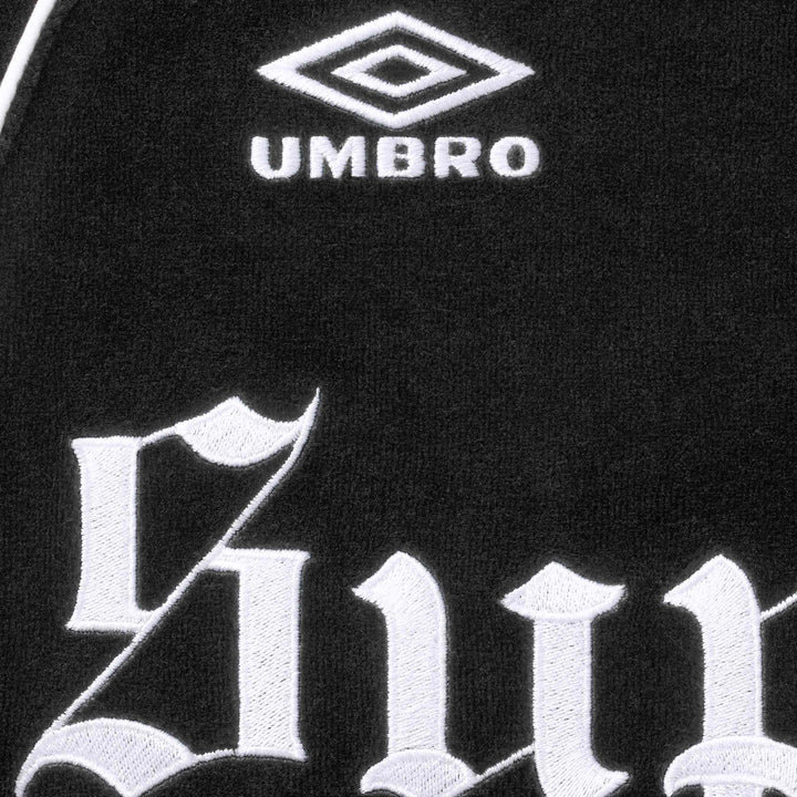 Close-up of the Umbro double diamond logo and blackletter embroidery on the black velour jacket