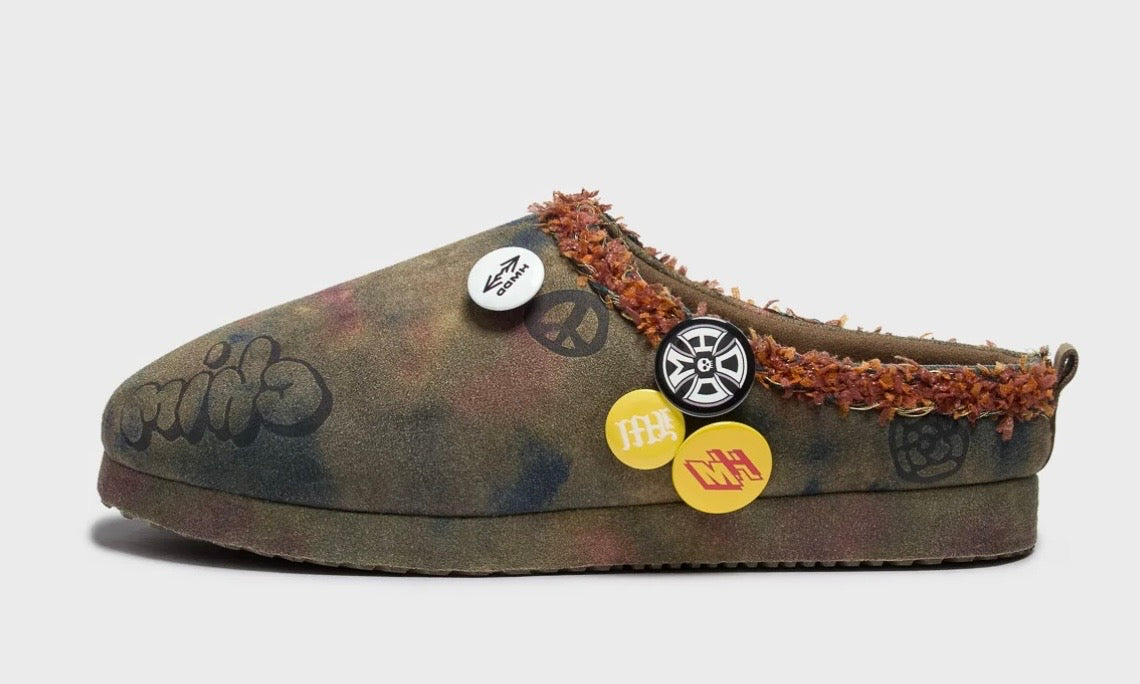 HMDD Graffiti Mule, side view of the washed camo suede clog with a wheel pin, yellow pins and a brown rubber sole